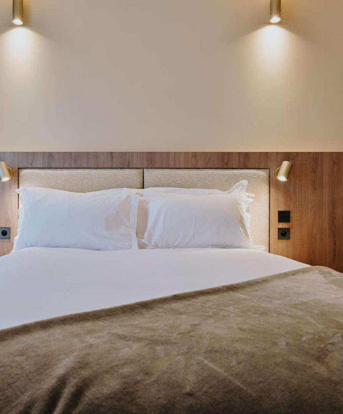 vue de face d'un lit avec une décoration murale en bois dans notre hôtel à confluence Lyon - Keystone